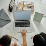 Overhead view of a mother helping her daughter with online learning at home.
